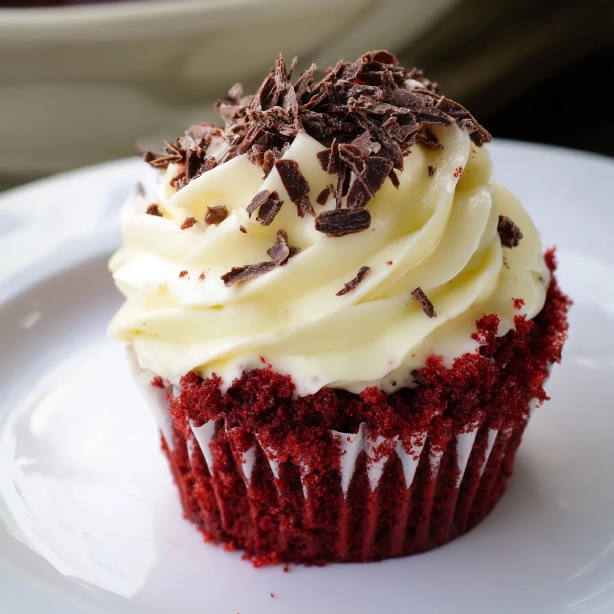 Freshly baked Red Velvet Cupcakes with cream cheese frosting sit on a wire rack, their vibrant red crumbs peeking from beneath fluffy white swirls.
