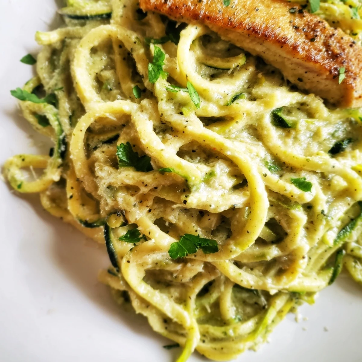 Creamy Chicken Alfredo with zucchini noodles tossed in a rich Parmesan garlic sauce, garnished with fresh parsley for a low-carb dinner.