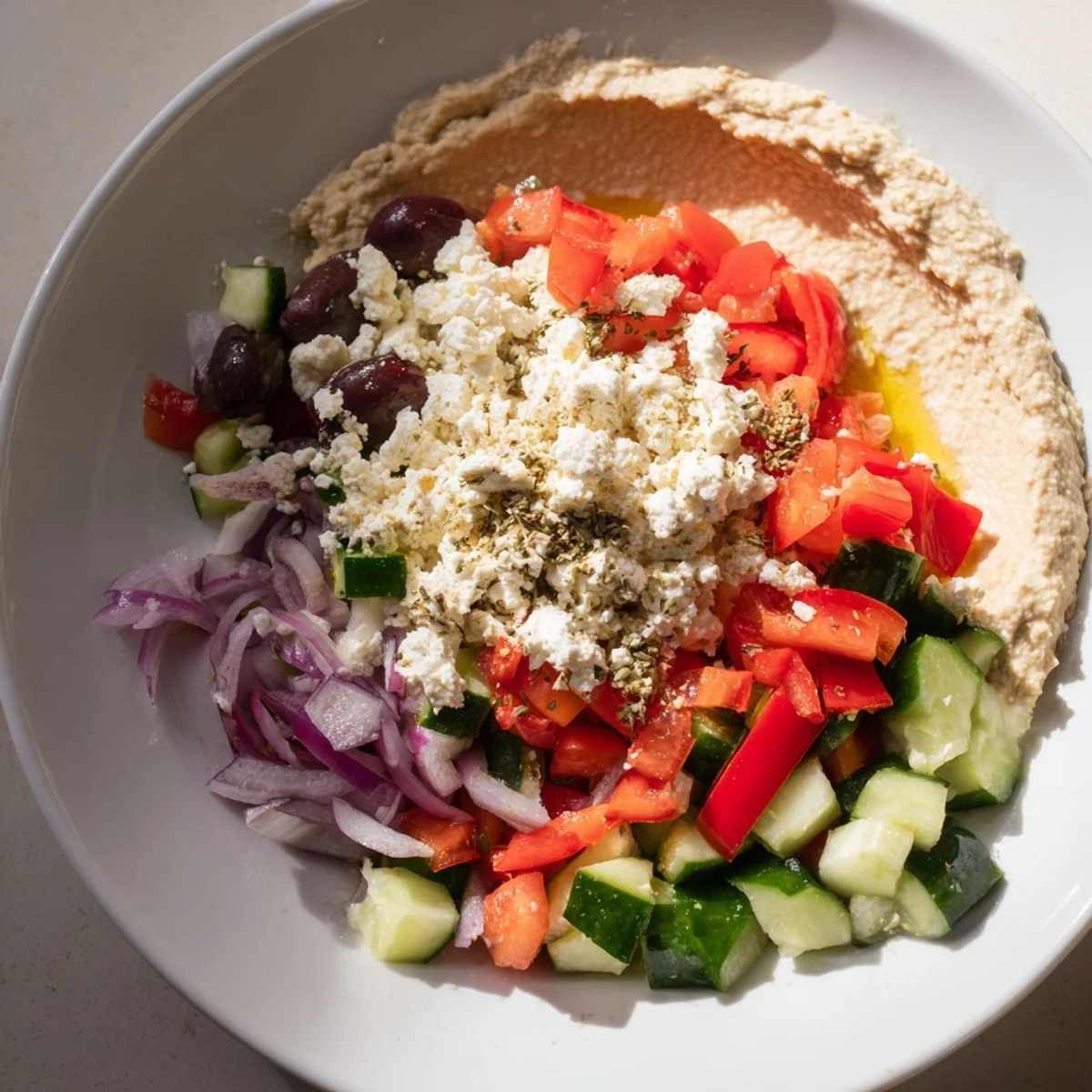 Colorful Mediterranean Salad with Hummus and Pita features a bed of romaine lettuce, chopped veggies, and feta, paired with smooth hummus and warm pita on the side.