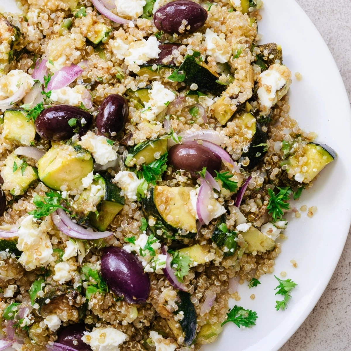 Hearty Mediterranean Quinoa Salad with Roasted Veggies in a white bowl, garnished with fresh mint and parsley, perfect for a gluten-free lunch or side dish.