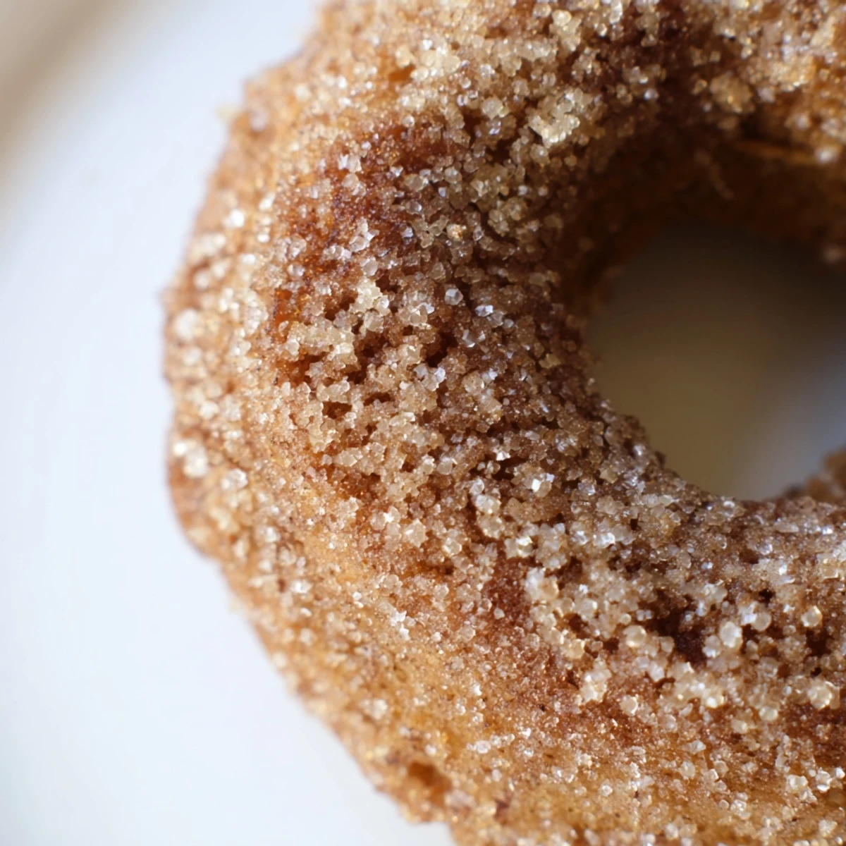 Freshly baked Baked Apple Cider Donuts with sugar glaze arranged on a cooling rack next to a mug of steaming hot apple cider.