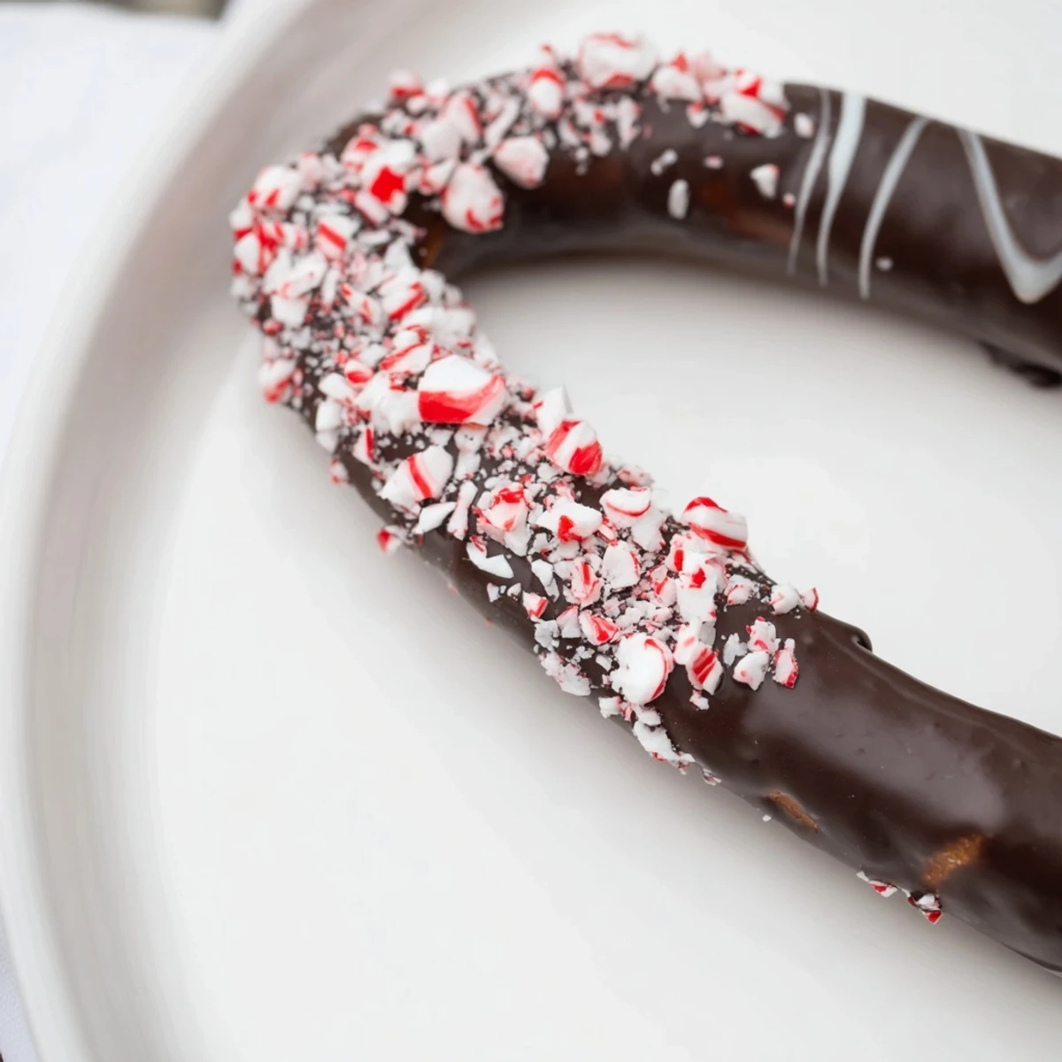 Close-up of a dark chocolate peppermint bark pretzel showing thick dark chocolate coating and minty texture.
