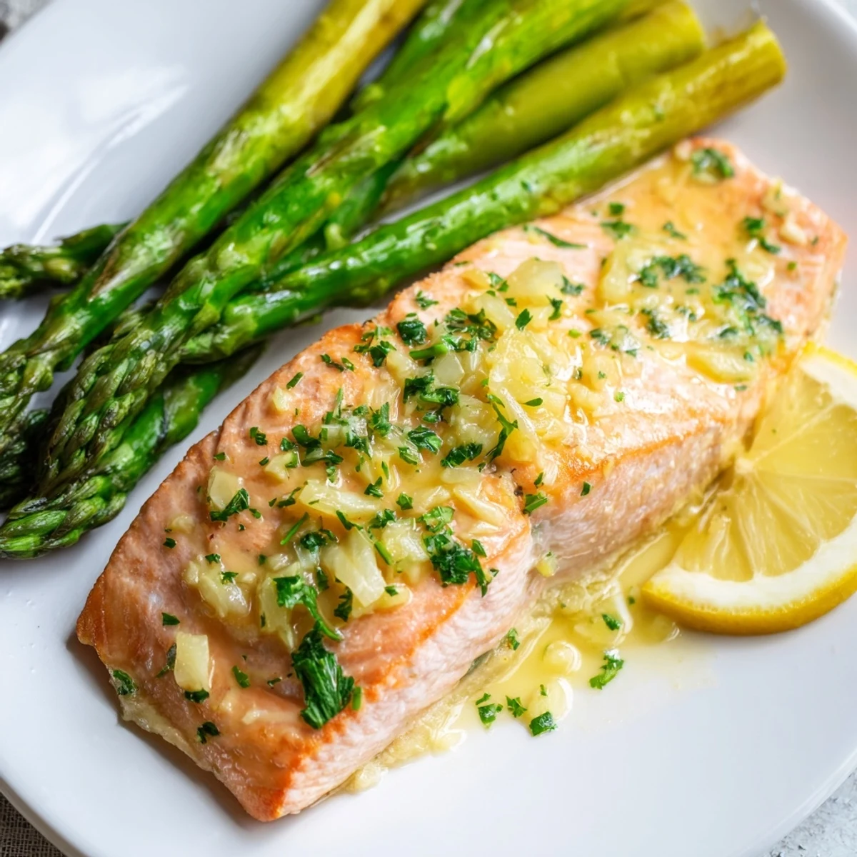 Fork-tender Lemon Garlic Butter Salmon with Asparagus Spears, glistening with a rich lemon garlic butter sauce and fresh parsley garnish.