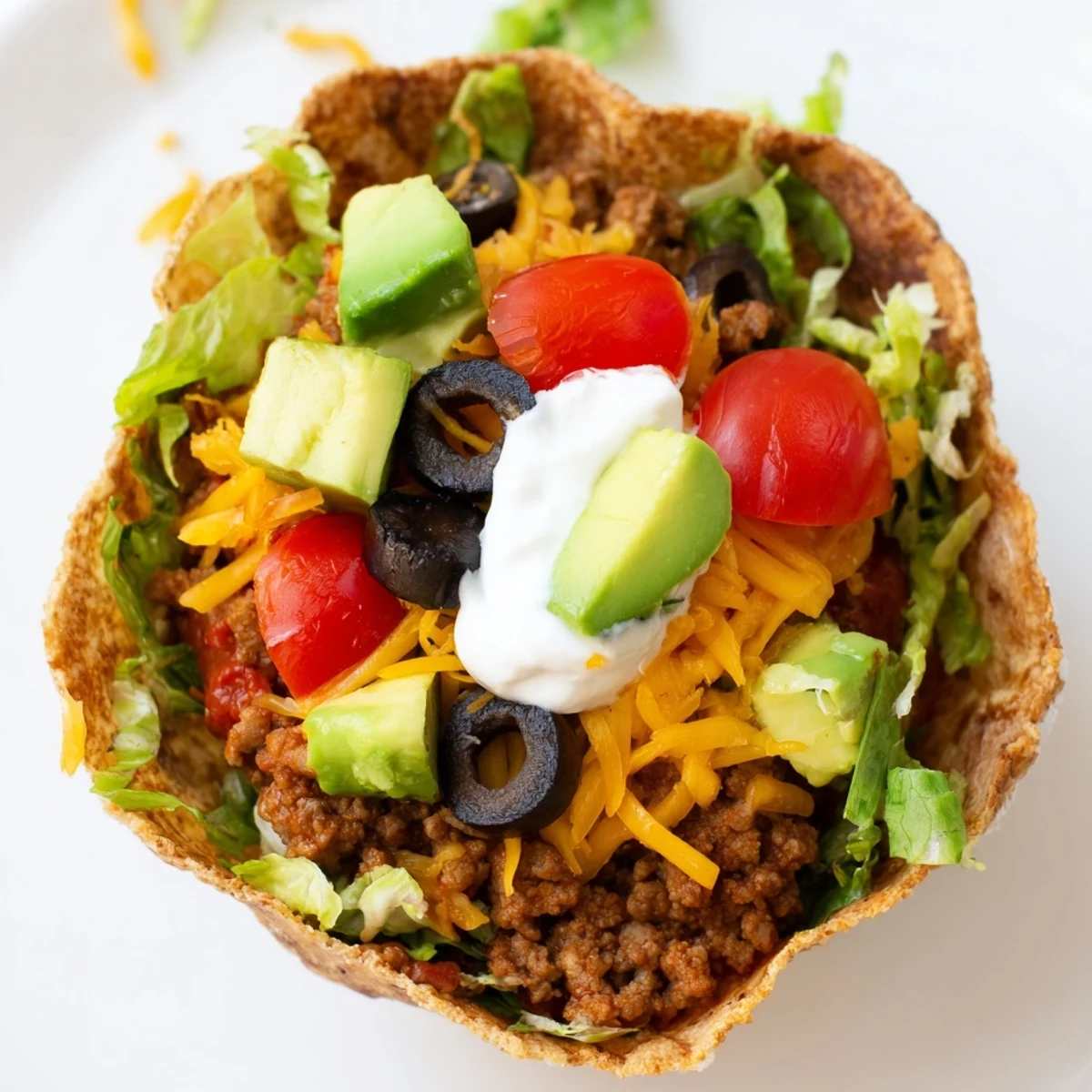 A crispy baked tortilla bowl holds seasoned beef, crisp lettuce, and avocado for a vibrant Beef Taco Salad.