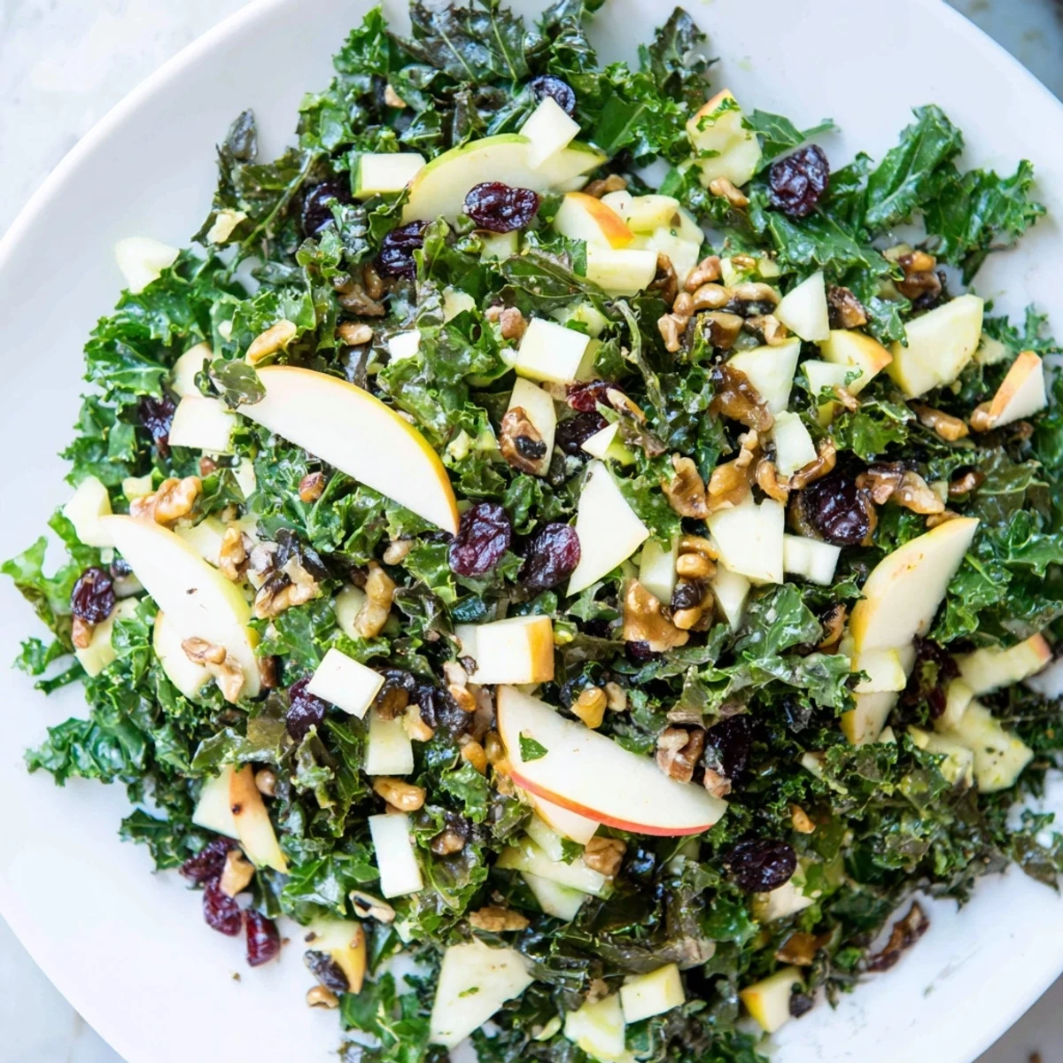 Vibrant winter kale salad with crisp apples, sharp cheddar cubes, and pecans tossed in a zesty apple cider vinaigrette, ready for a festive holiday table.