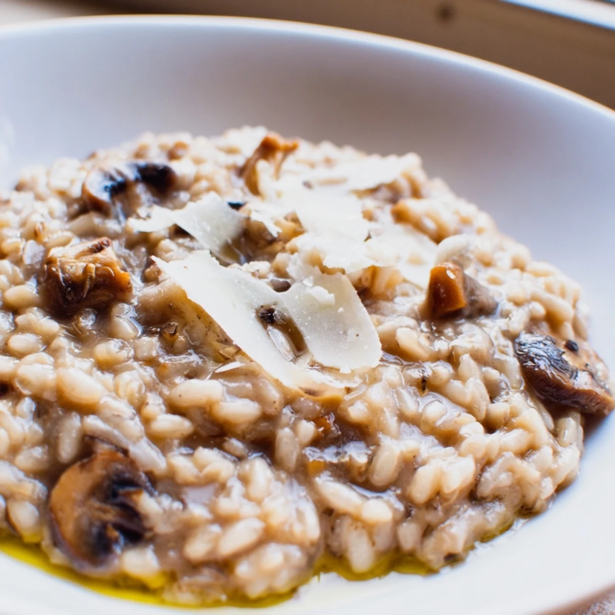 Creamy Mushroom Risotto with Truffle Oil steams in a shallow bowl, featuring rich brown mushrooms and a glistening drizzle of dark truffle oil.