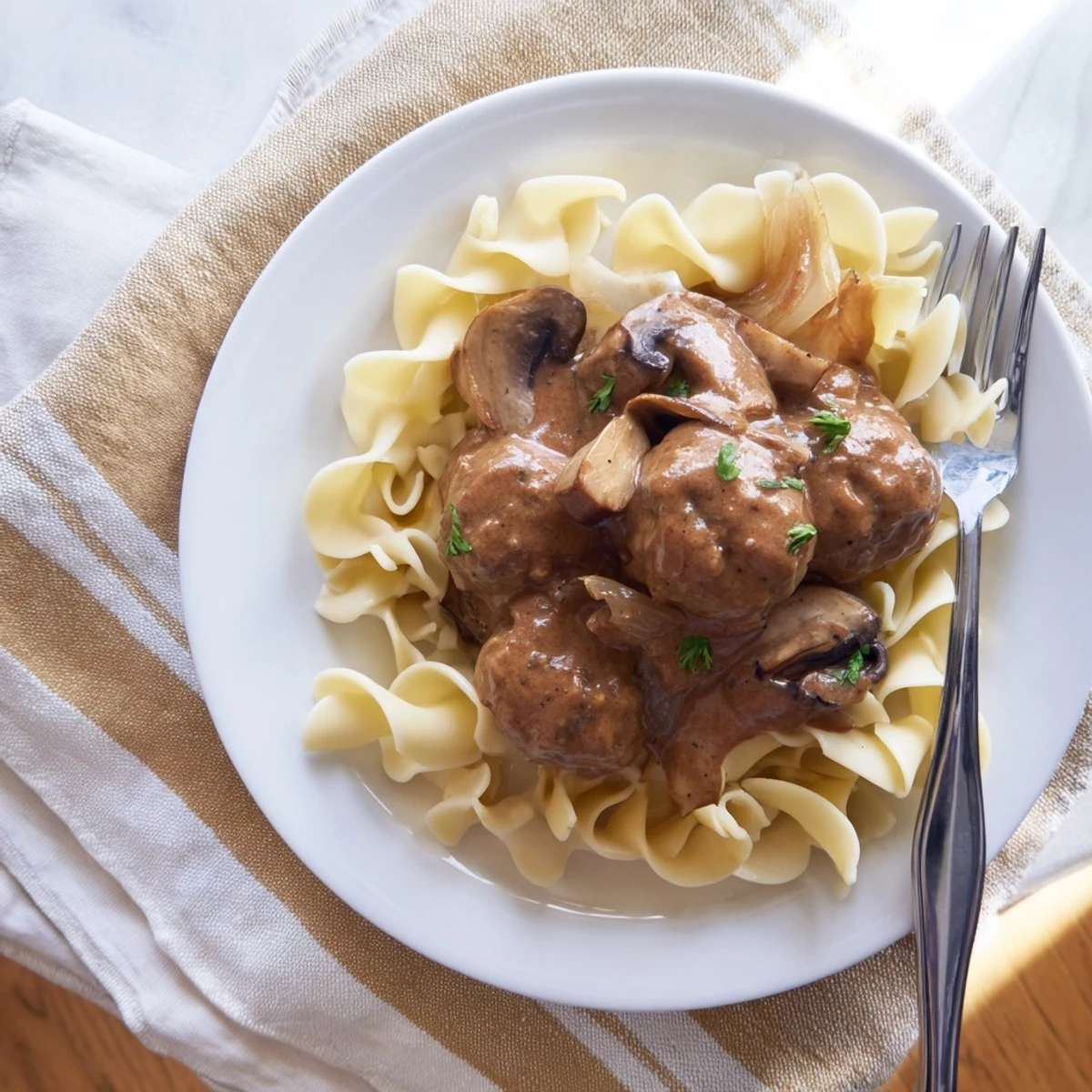 Close-up of a fork lifting turkey meatballs and noodles from a rich, creamy stroganoff, highlighting its hearty texture.
