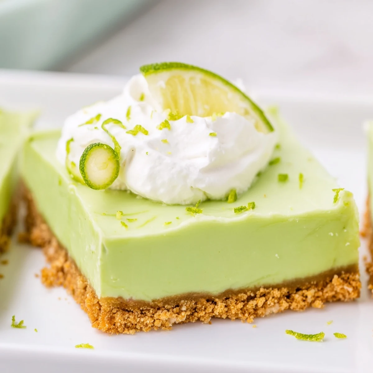 Fresh lime slices and zest top the vibrant St. Patrick's Day Key Lime Pie Bars, served on a festive green plate.