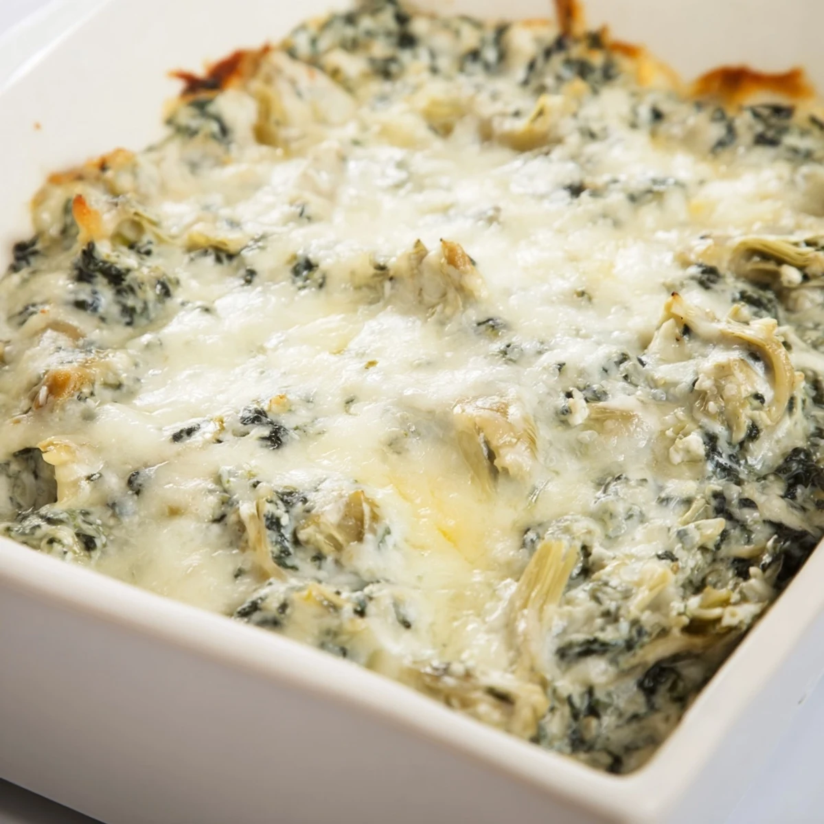 Warm, bubbly Creamy Spinach and Artichoke Dip with Baguette fresh from the oven, golden crust visible.
