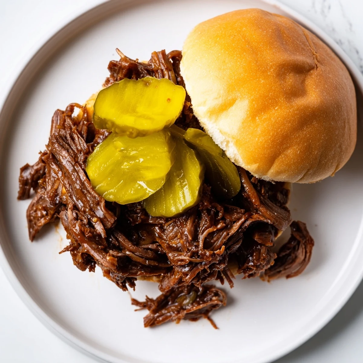 Golden-brown, tender pulled beef sliders with dill pickle slices on buttered buns, ready to serve for game day.