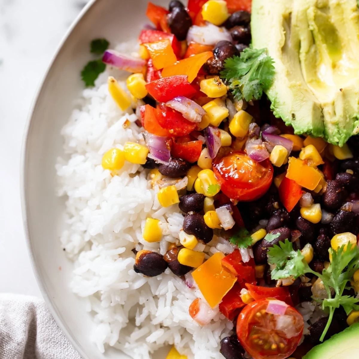 A vibrant bowl of Cajun Spices Veggie Rice Bowl with colorful peppers, corn, and black beans topped with fresh cilantro.  