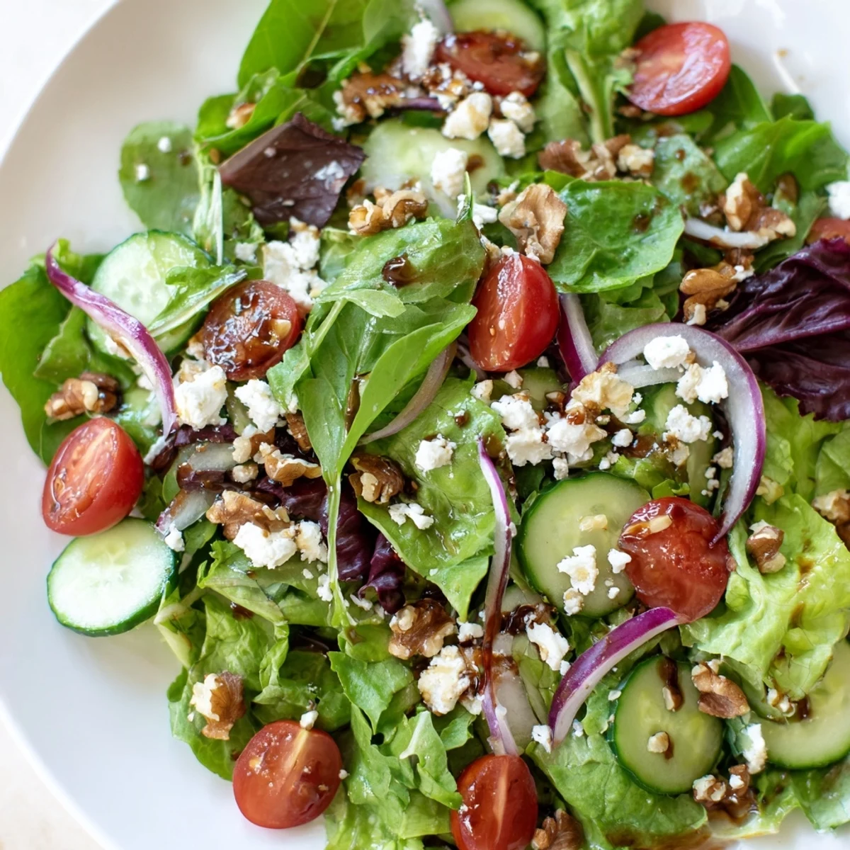 Vibrant spring mix salad with cherry tomatoes, cucumber, and creamy feta, tossed in zesty homemade balsamic vinaigrette.