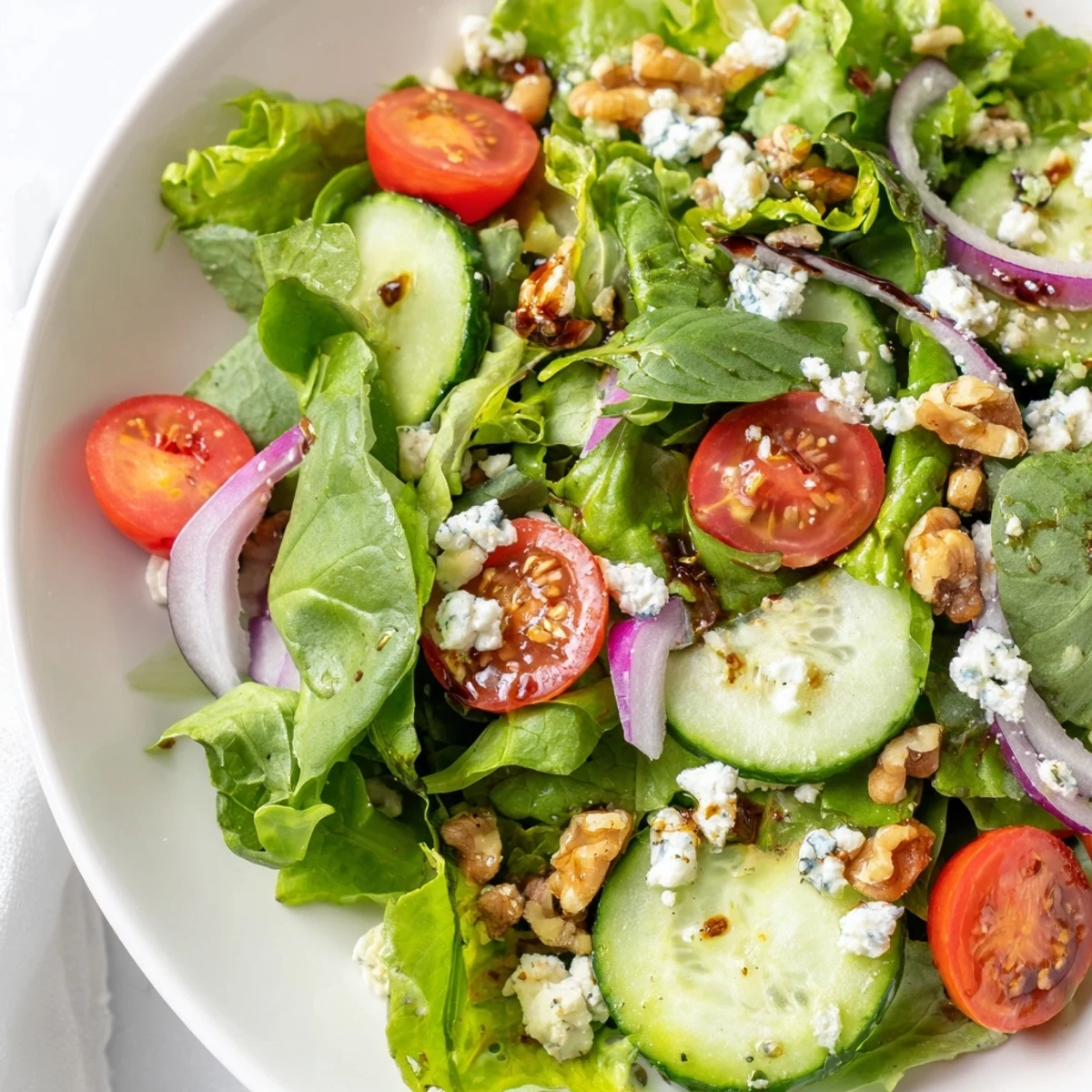 Close-up of a colorful Spring Mix Salad with Vinaigrette, featuring glistening greens and red onions, ideal for a light lunch side.