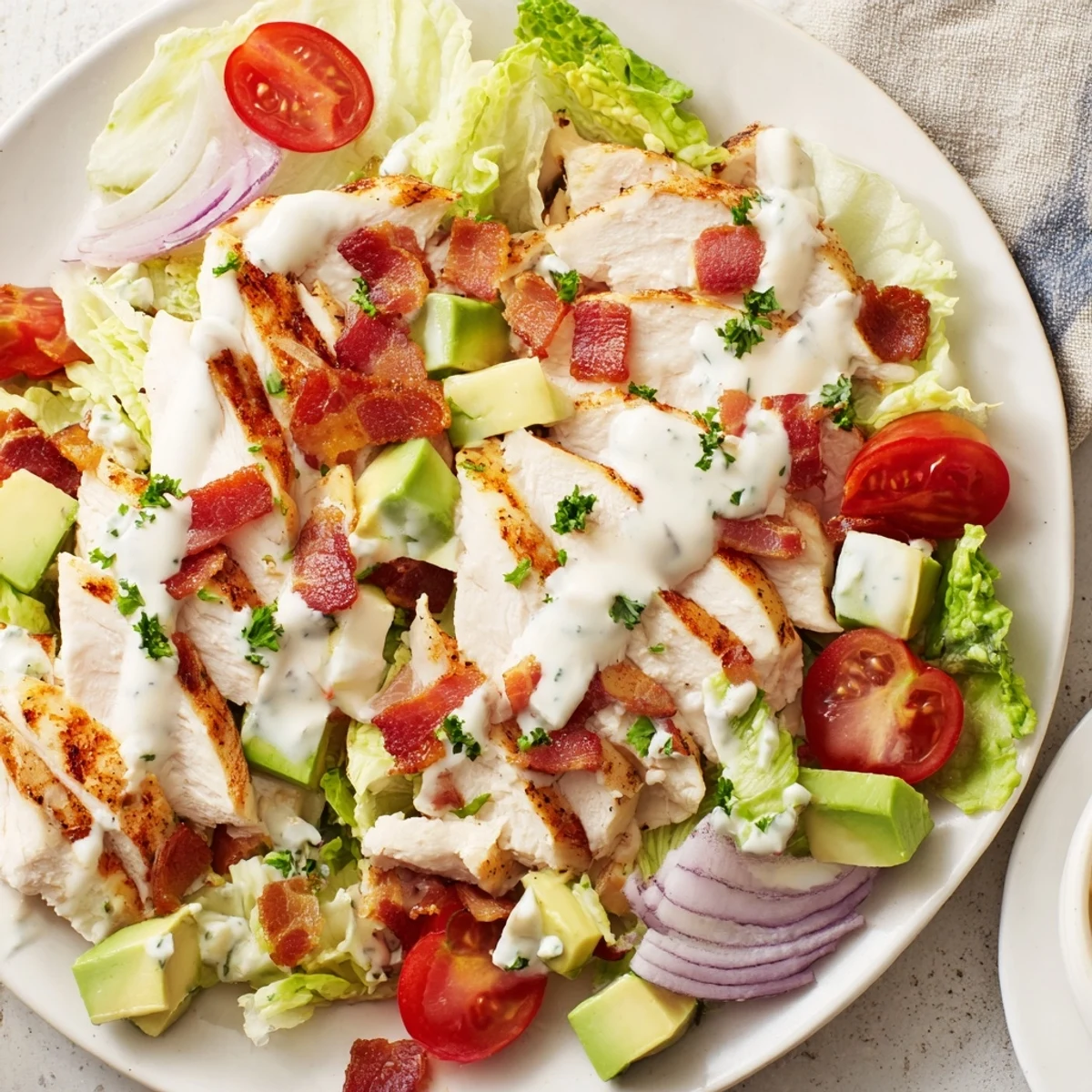 A vibrant BLT Chicken Salad served on a plate with creamy dressing and a sprinkle of black pepper.