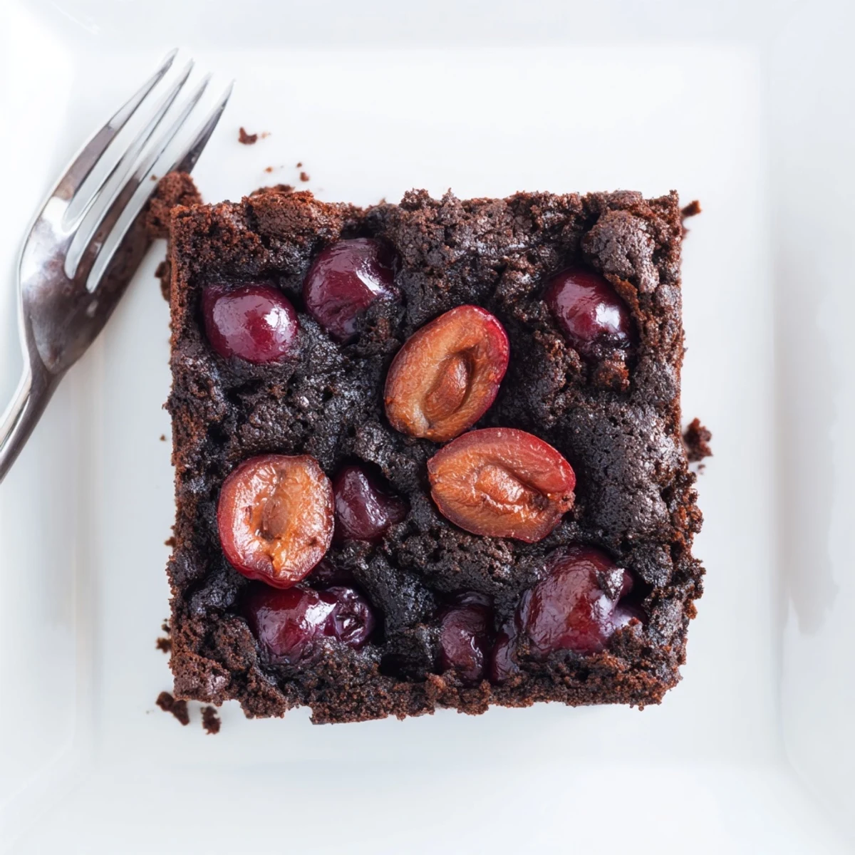 Warm, gooey Roasted Cherry Brownies squares topped with caramelized cherries and a dusting of cocoa.