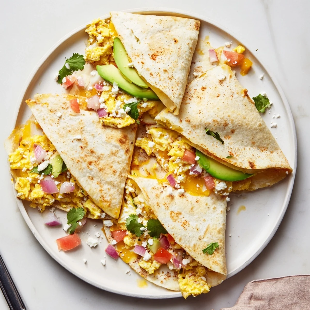 Overhead shot of Spicy Avocado Egg and Three Cheese Quesadillas served with sour cream and lime wedges on a colorful plate, perfect for dinner.