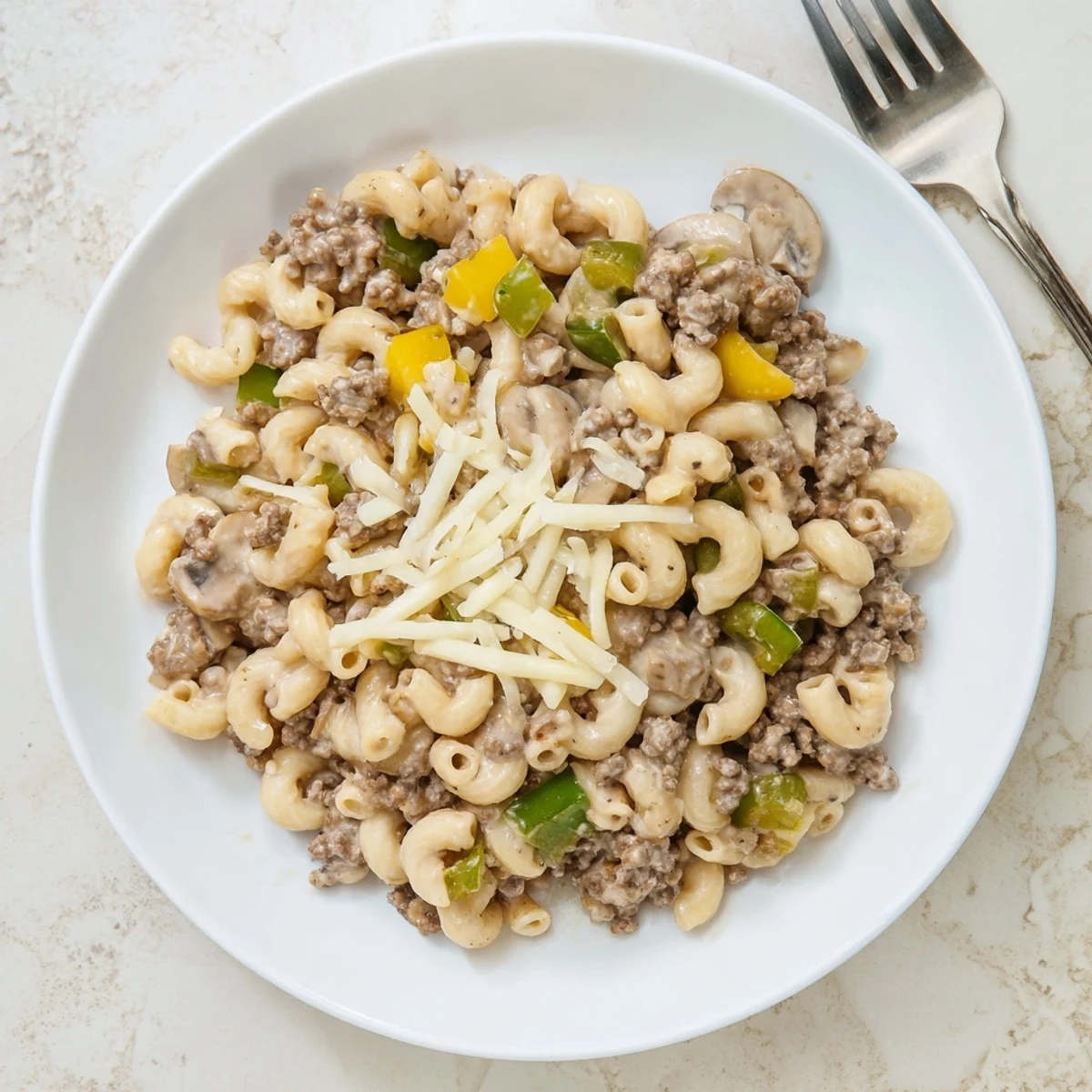 A bowl of Easy High Protein Philly Cheesesteak Mac topped with melted provolone and mozzarella, served steaming hot.