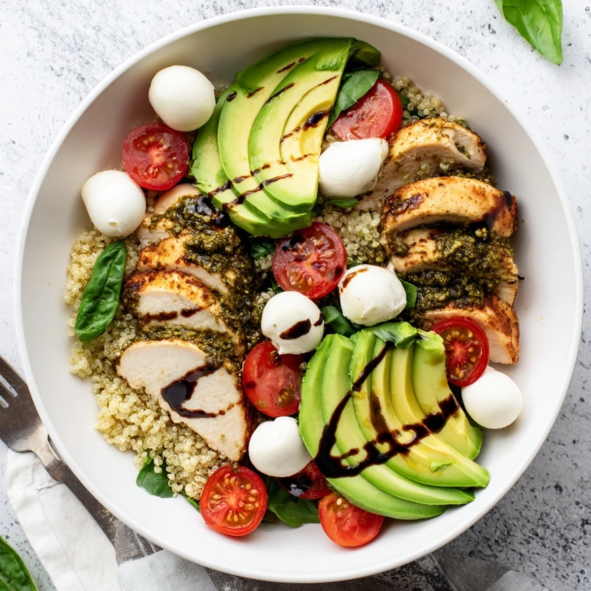 Savor this Pesto Chicken Caprese Grain Bowl with creamy avocado and a sweet balsamic glaze drizzle.