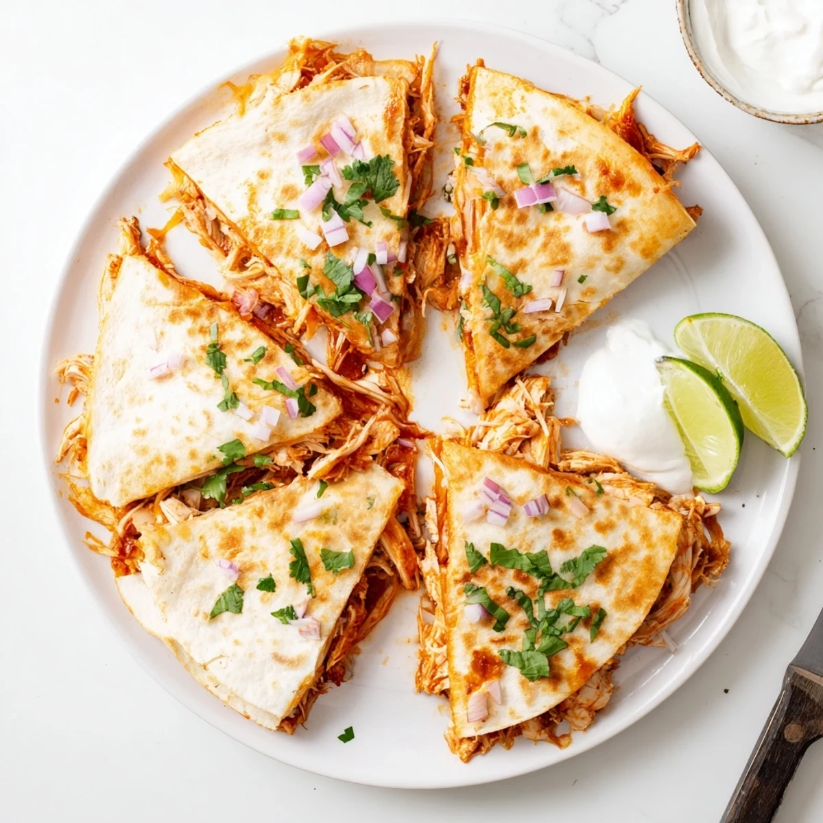 Golden-brown tortillas stuffed with shredded BBQ chicken, melted mozzarella, and cheddar, garnished with fresh cilantro and lime wedges.