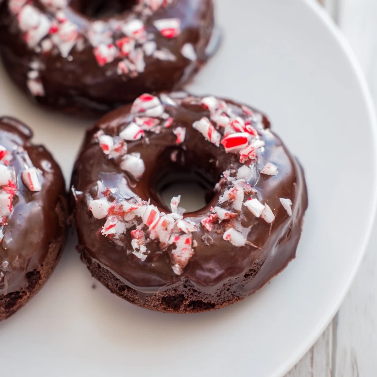 A close-up shows a Chocolate Peppermint Mochi Donut with a chewy texture, topped with glossy glaze and sparkling peppermint candy bits.