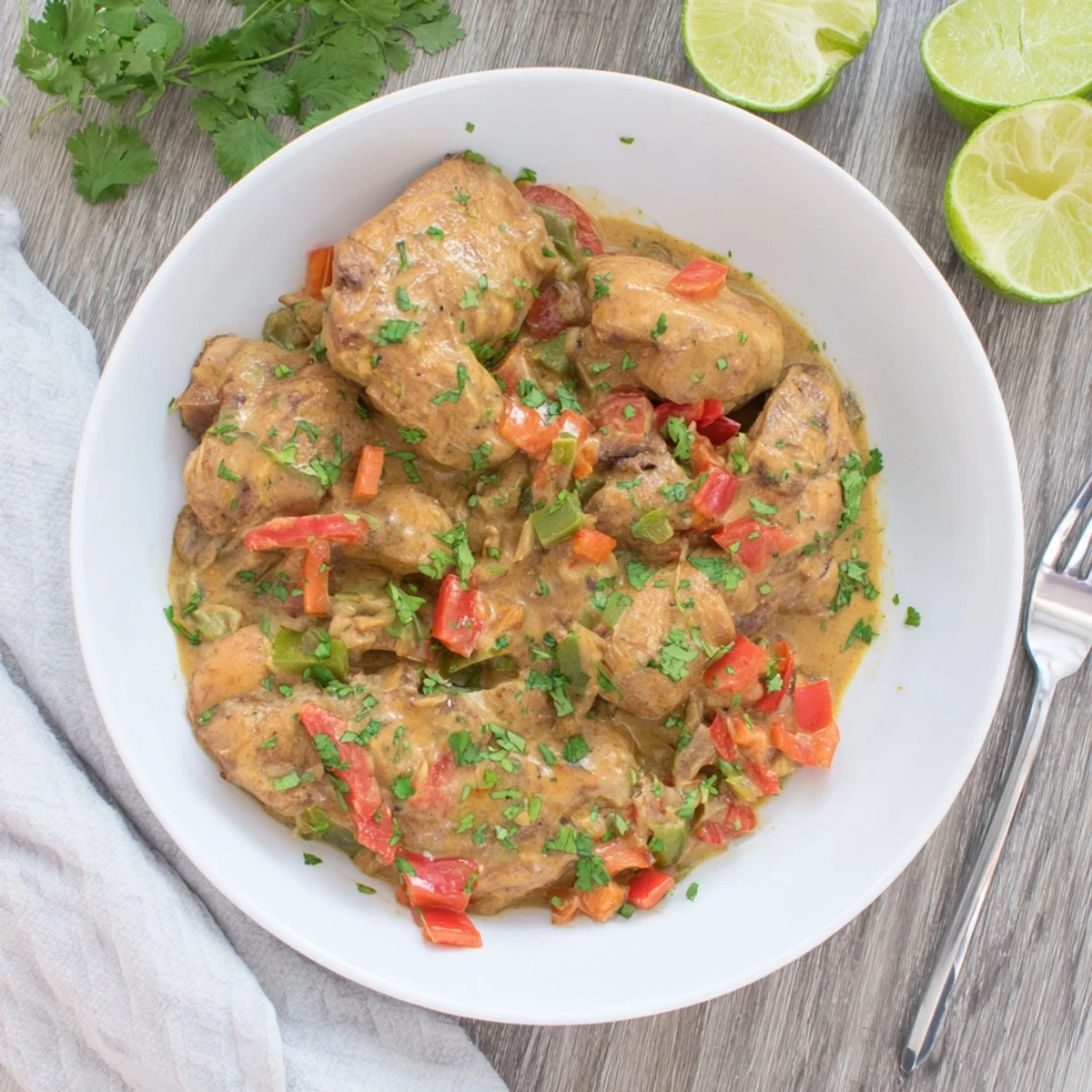 Golden chicken pieces swimming in creamy spicy Brazilian coconut sauce with vibrant bell peppers