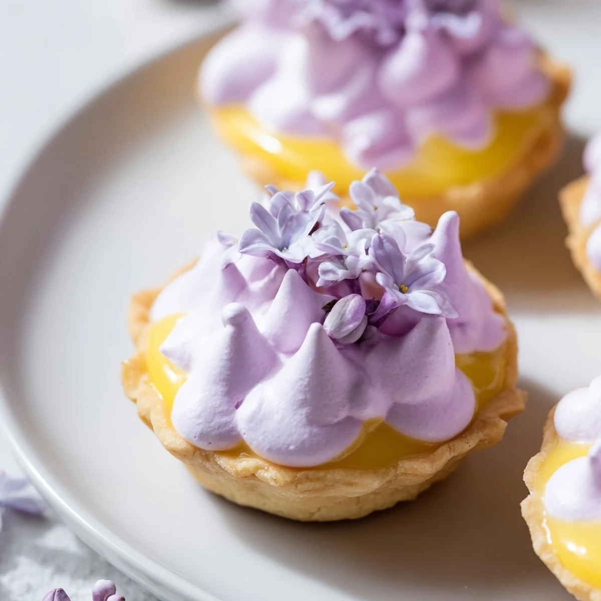 French-inspired mini lemon tart featuring crisp shell, lemon curd, and floral meringue