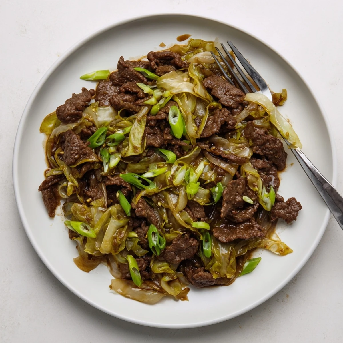 Golden brown low carb Mongolian ground beef served over tender cabbage strips with green onion garnish