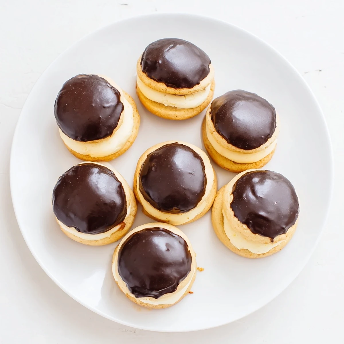 Mini Boston Cream Pie cookie bites arranged on a serving platter with chocolate dripping down the sides