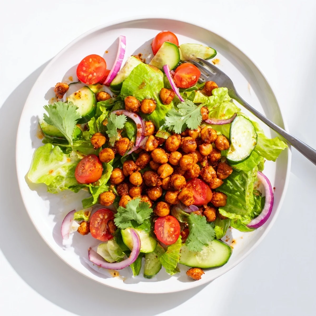 Close-up of zesty chickpea salad with crispy spiced beans scattered over crisp lettuce, bell peppers, and red onion
