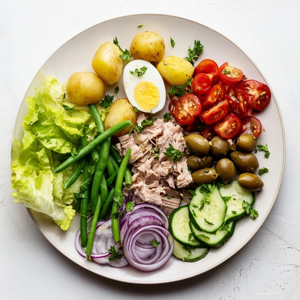 Golden Niçoise Salad plated with tuna, hard-boiled eggs, olives, and crisp vegetables drizzled with tangy vinaigrette