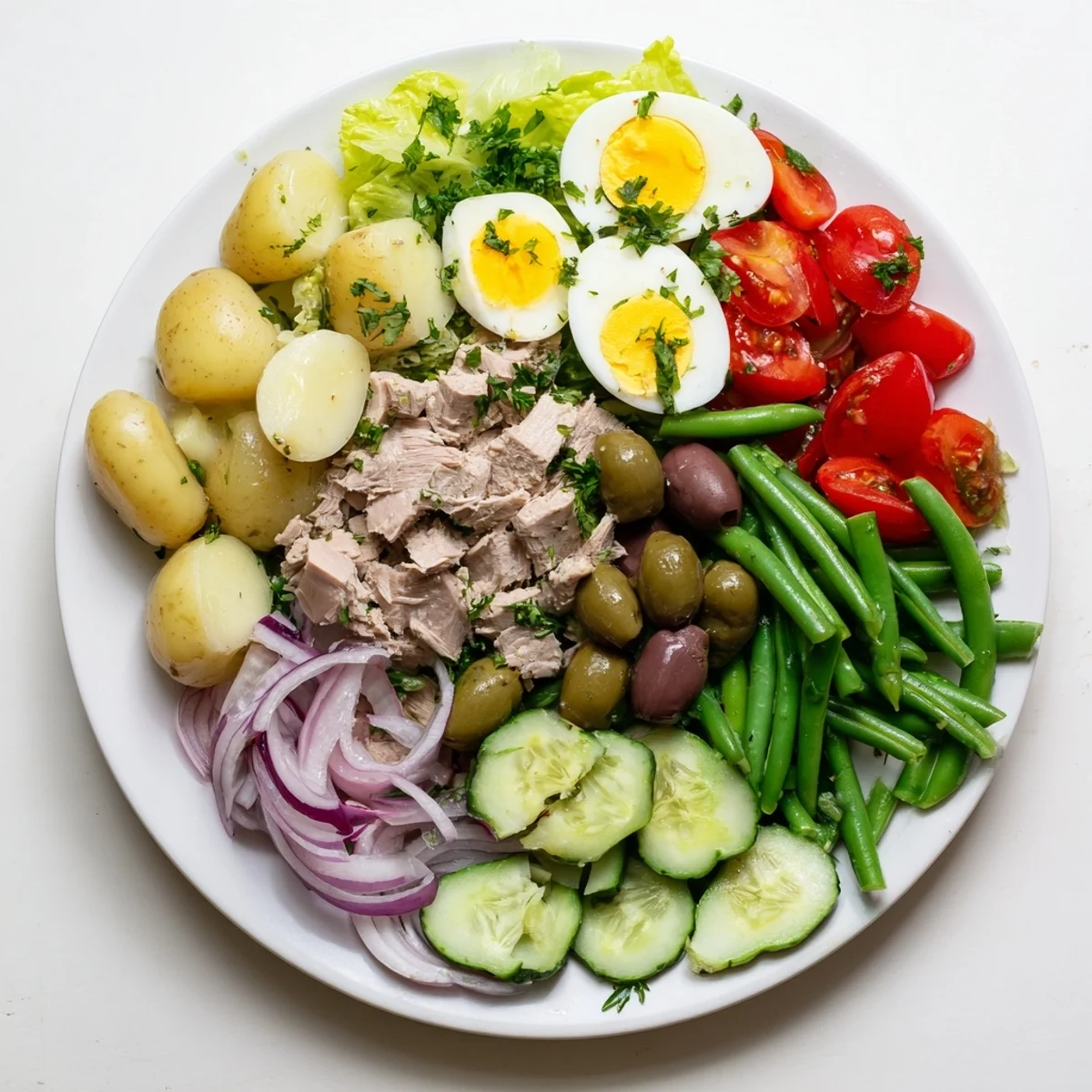Classic Niçoise Salad arranged on a platter with colorful vegetables, protein-rich tuna, eggs, and savory olives