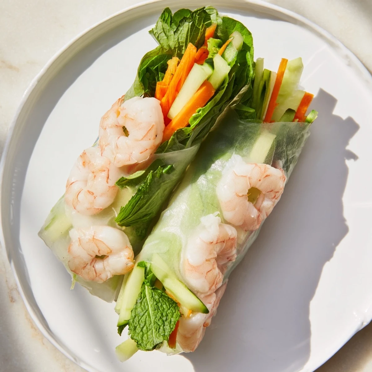 Golden fresh spring rolls with peanut sauce displaying crisp vegetables and pink shrimp through translucent rice paper