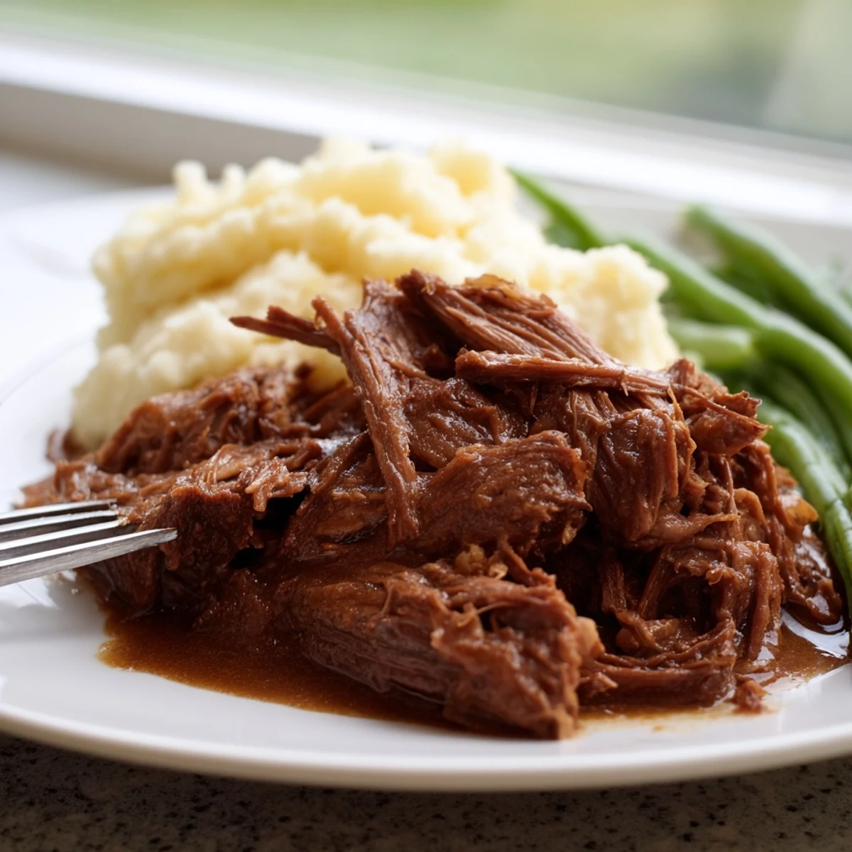 Tender Southern style pot roast plate with rich gravy served over creamy mashed potatoes and buttered green beans