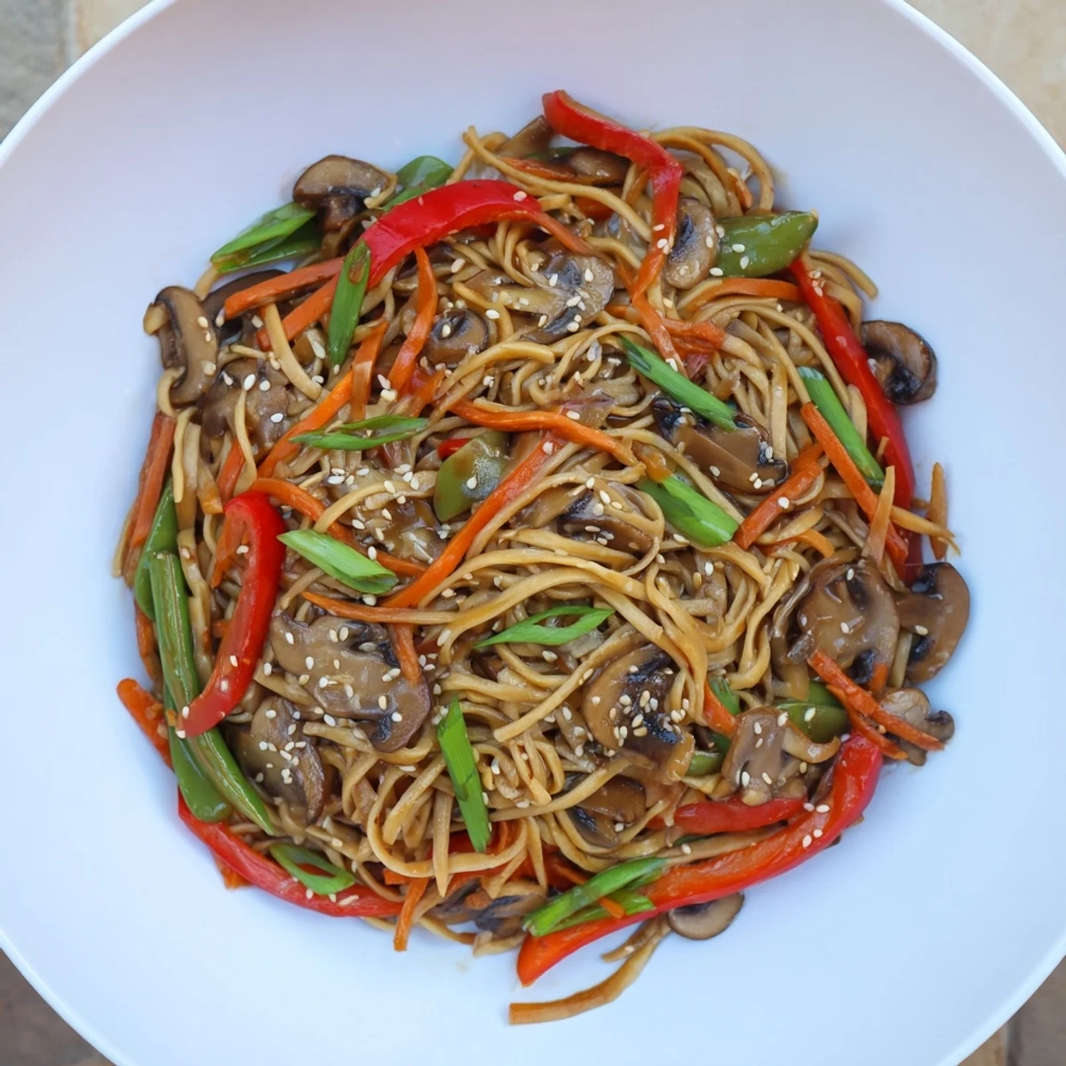 Golden garlic mushroom chow mein noodles tossed with colorful crisp vegetables in a dark savory sauce