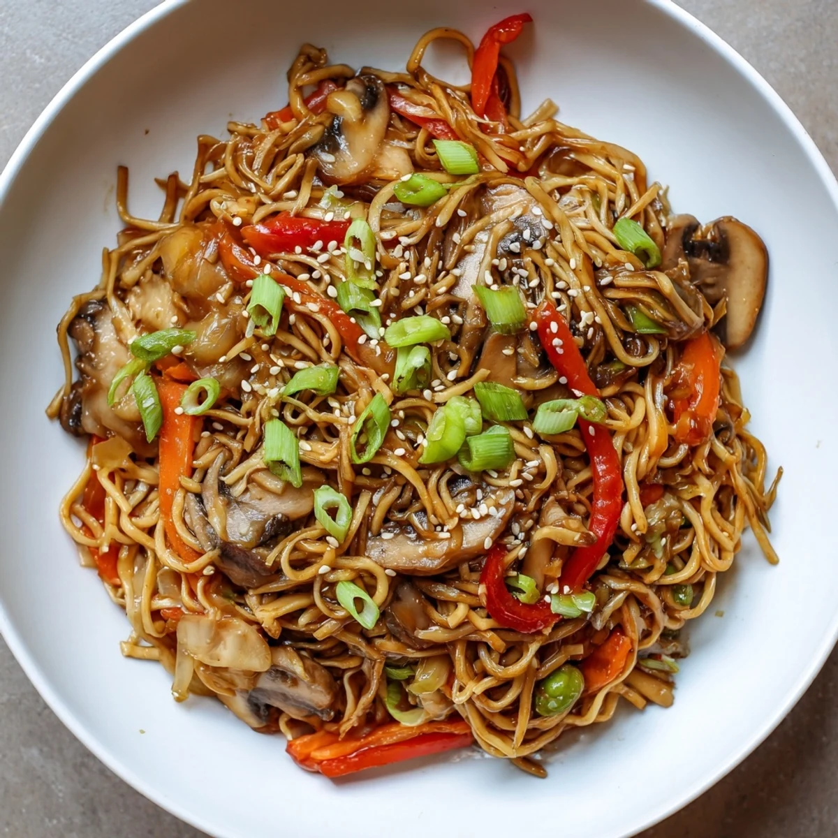Wok-fried garlic mushroom chow mein featuring tender noodles sliced peppers carrots and snap peas glistening