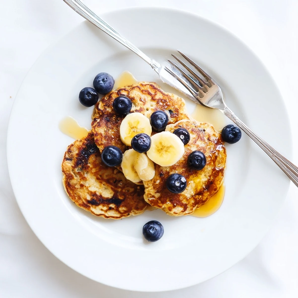 Golden brown stack of fluffy Greek yogurt banana pancakes drizzled with warm maple syrup
