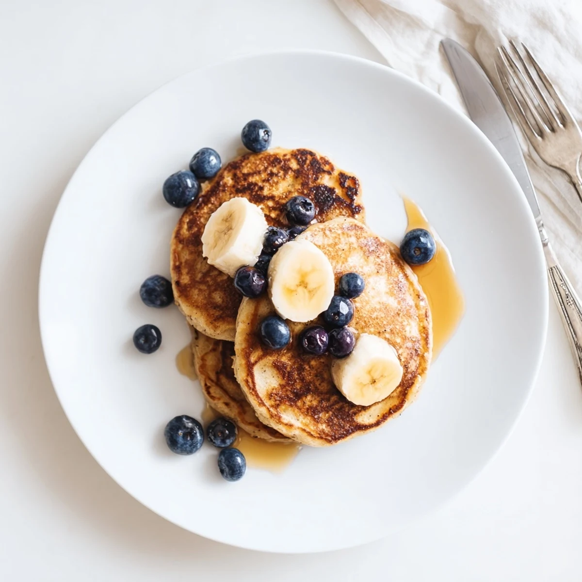 Wholesome breakfast spread featuring Greek yogurt banana pancakes served with butter and colorful berries