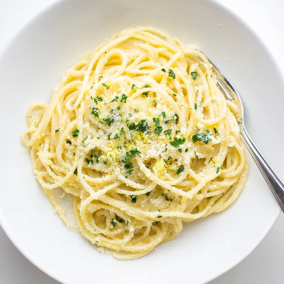 Golden garlic butter pasta dish served in white bowl with grated cheese topping