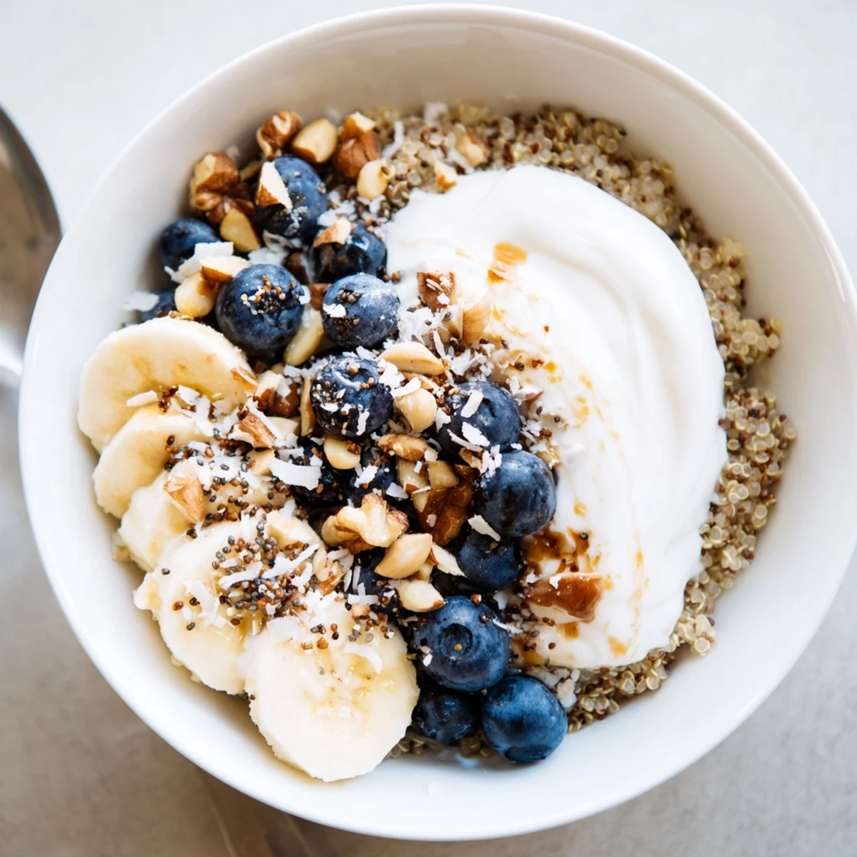 Golden quinoa breakfast bowl with juicy blueberries, sliced banana, and maple syrup drizzle