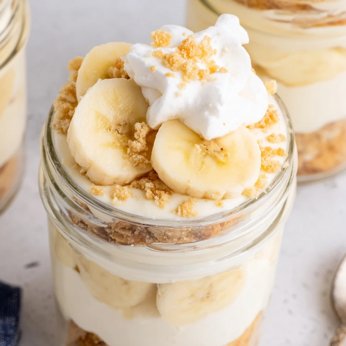 Individual no bake banana pudding cheesecake cups with swirled layers and crunchy vanilla crust
