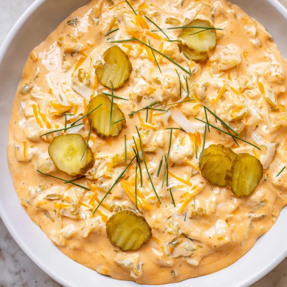 Tangy Buffalo pickle dip topped with cheddar cheese and fresh chives ready for game day snacking spread