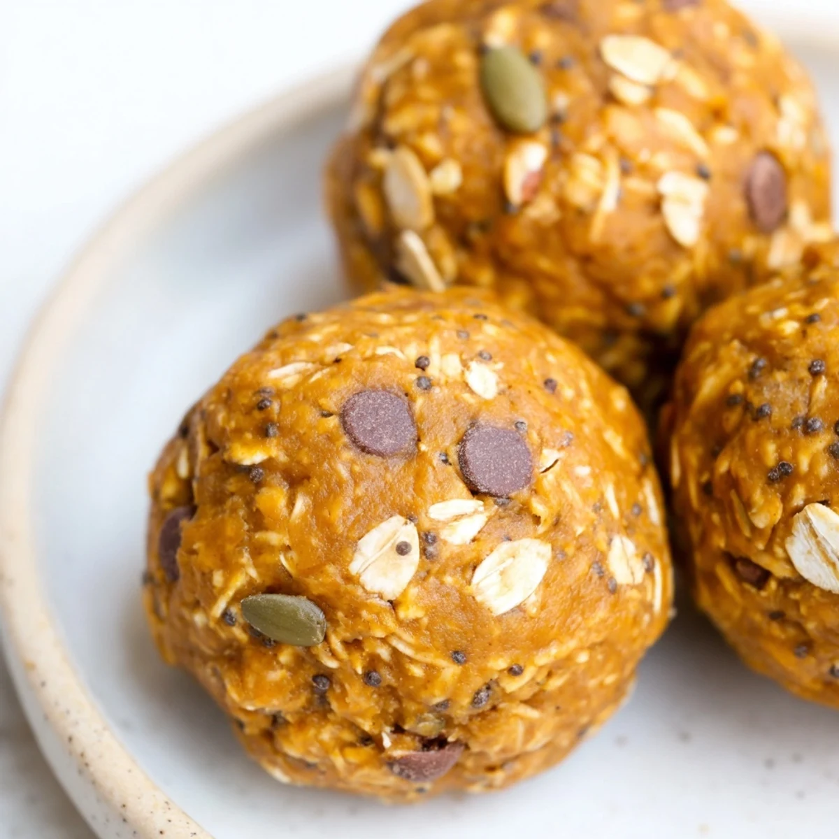 Golden no bake pumpkin protein balls arranged on parchment with warm cinnamon spice