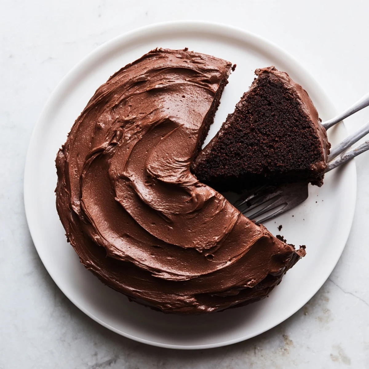 Matildas Chocolate Cake served on a white plate with rich chocolate buttercream coating the sides and top