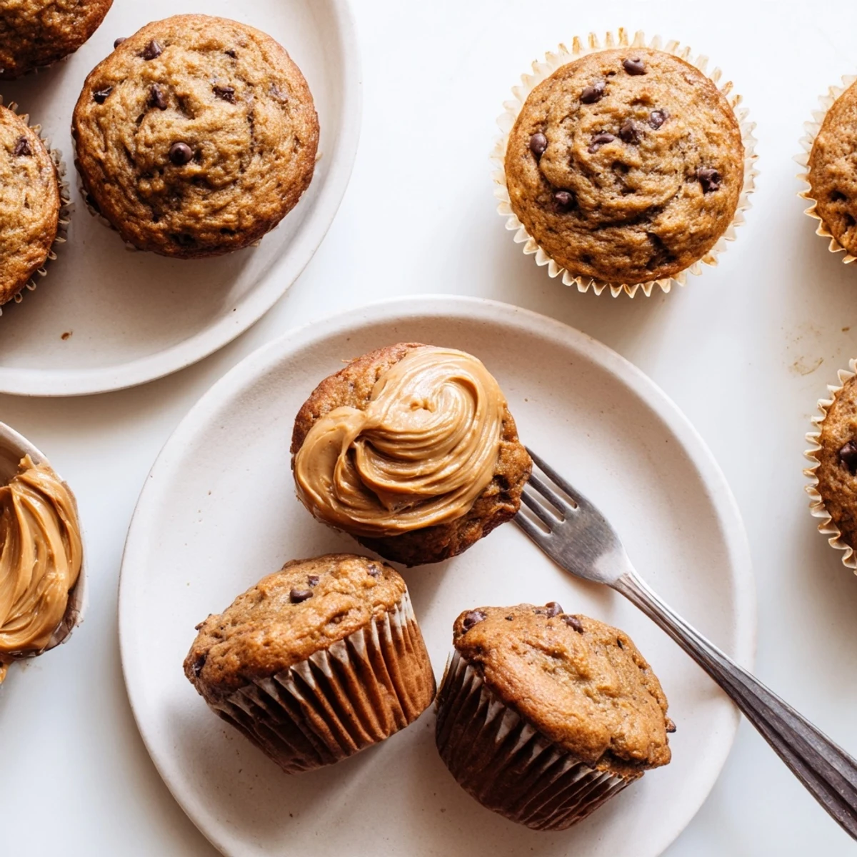 Freshly baked peanut butter banana muffins topped with melted chocolate chips on a wooden board