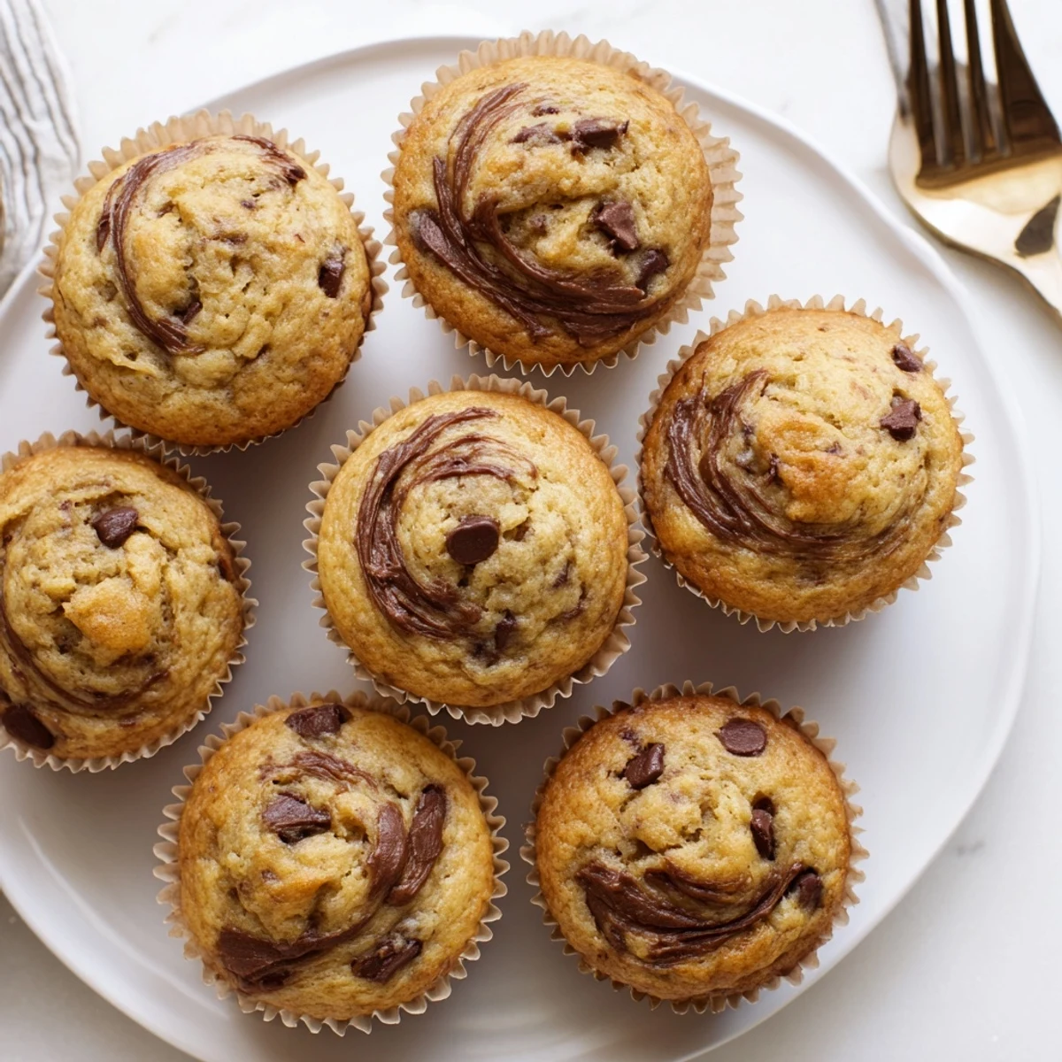 Golden peanut butter banana muffins with domed tops cooling on a wire rack