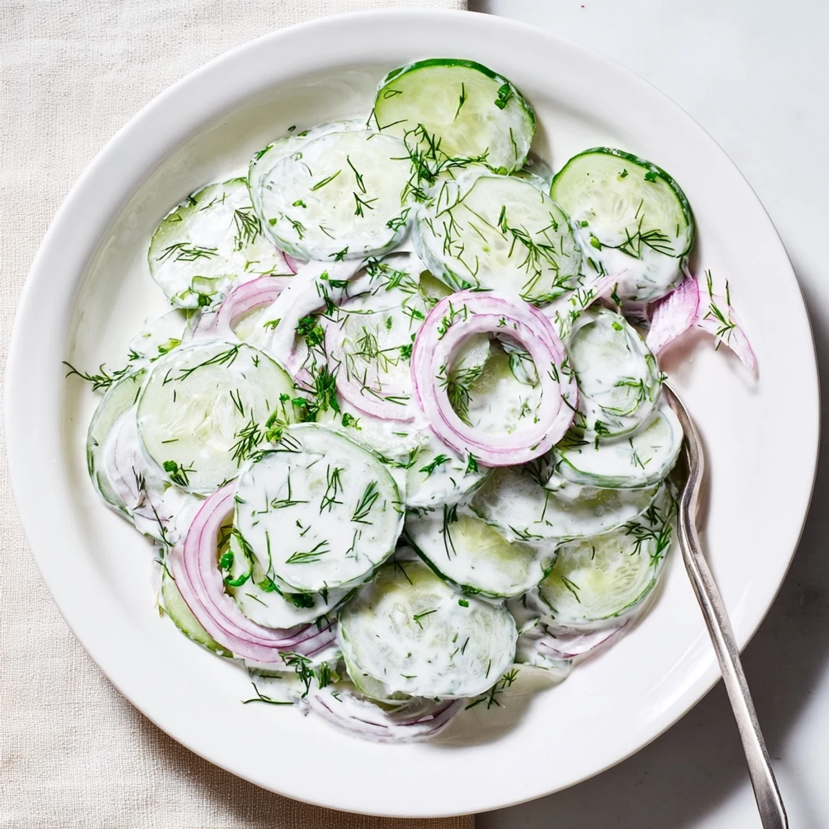 Refreshing cucumber dill salad with crisp sliced cucumbers in creamy tangy dressing garnished with fresh herbs