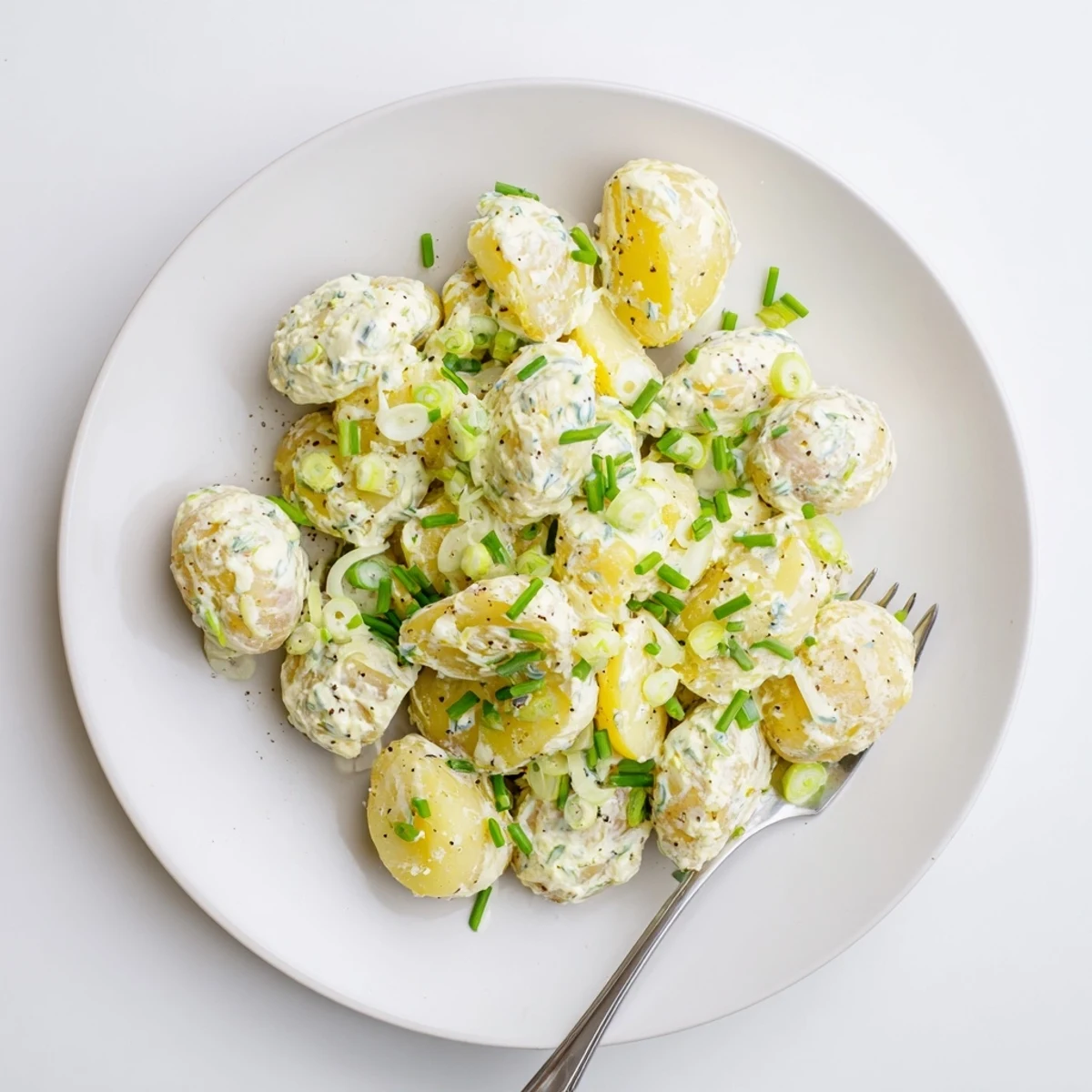 Sour Cream And Onion Potato Salad glistening with creamy dressing and fresh chives