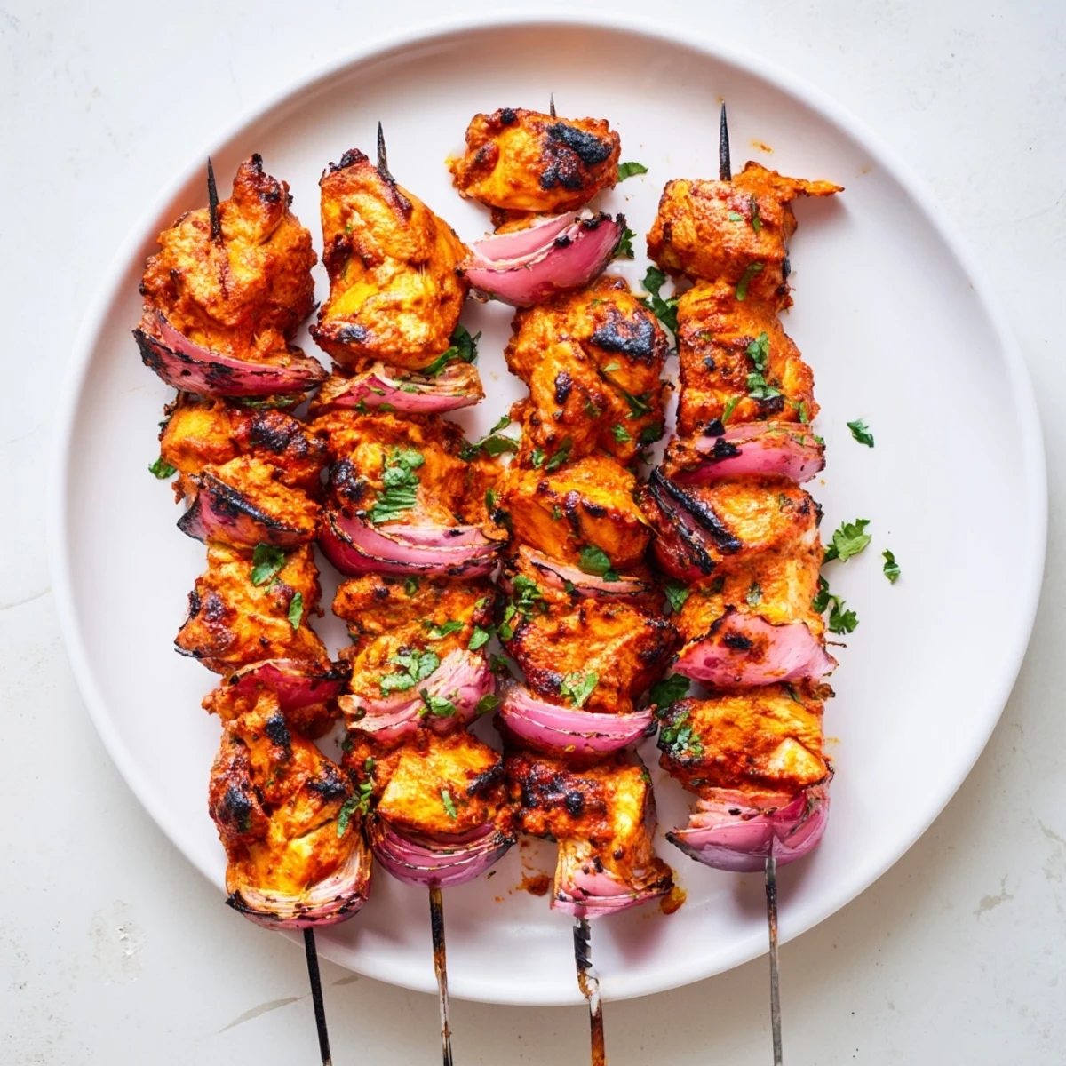 Plated Tandoori Chicken Tikka Skewers served with mint chutney and warm naan.