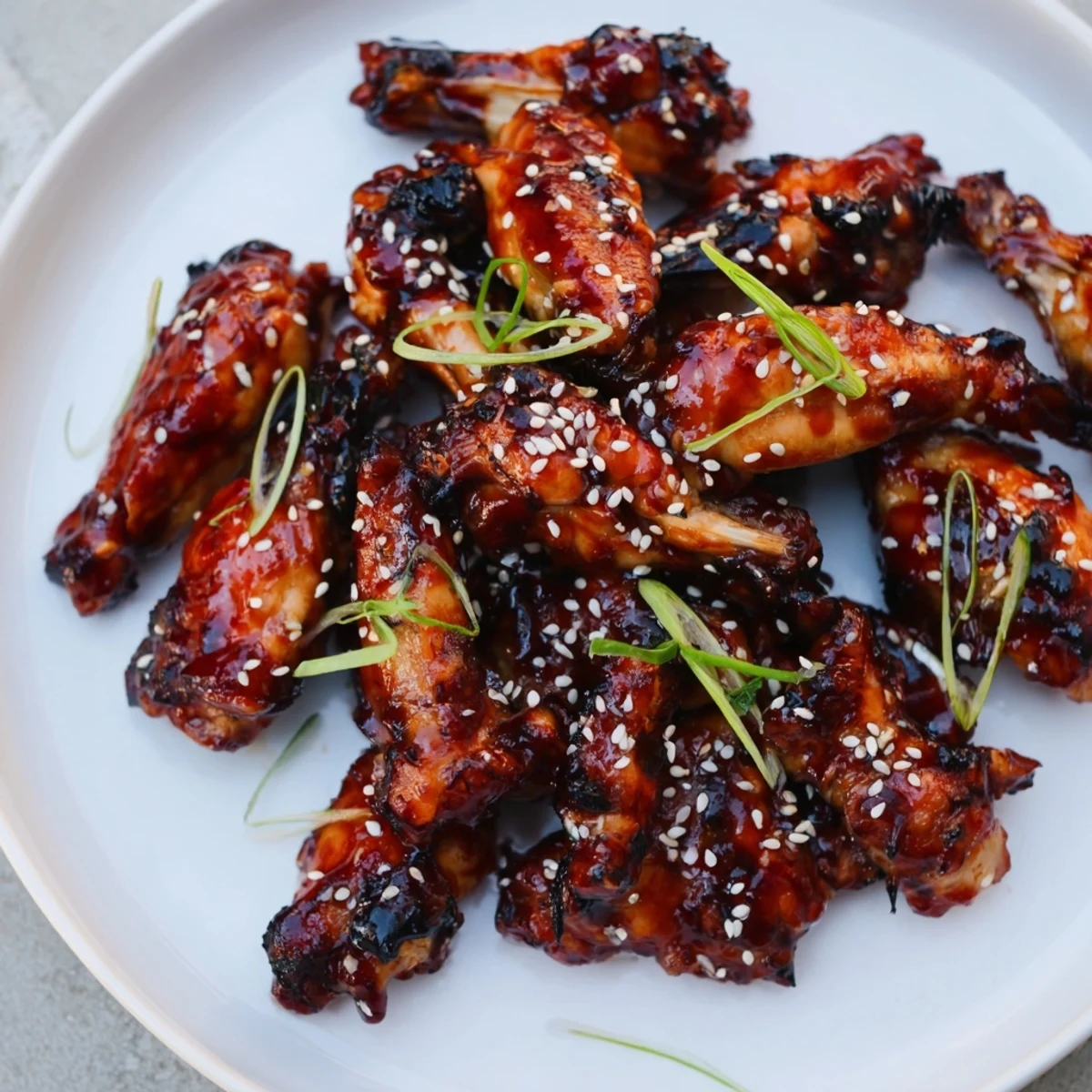 Warm Sticky Teriyaki Baked Wings piled on a platter, sesame-speckled