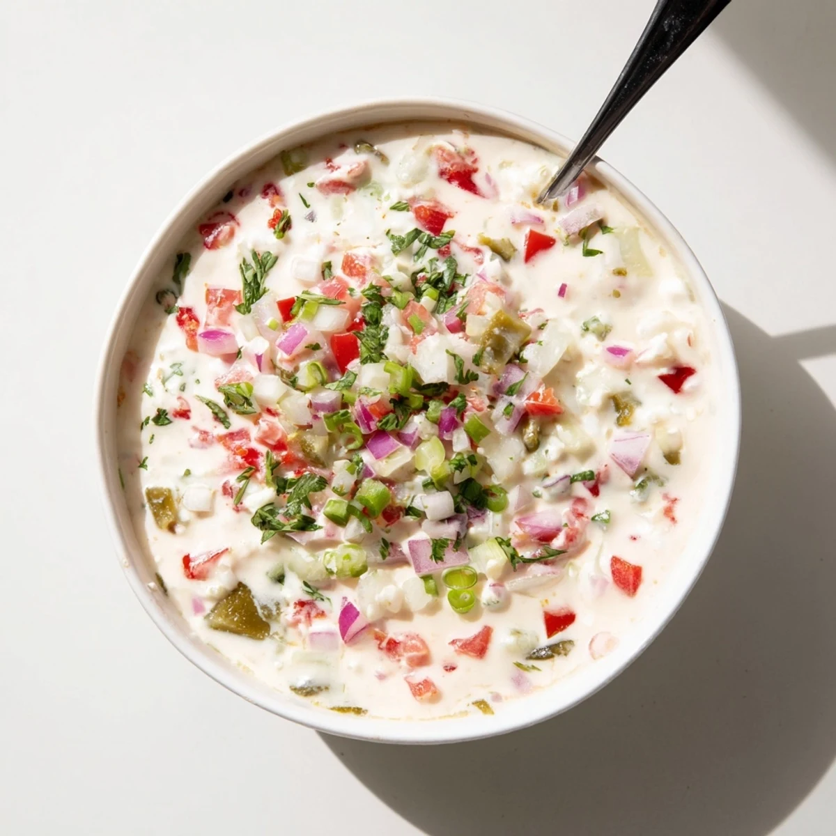 Thick white Grillos Pickle De Gallo Ranch Dip topped with fresh diced tomatoes, red onions, and chopped green onions